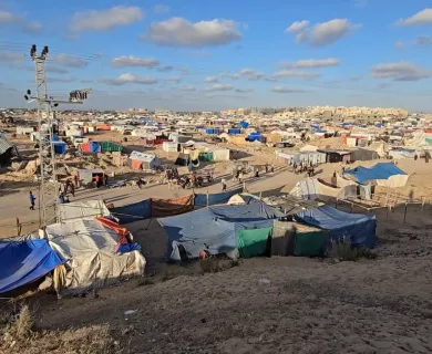 Tents in a wide camp. Sky is blue with some spreaded clouds.